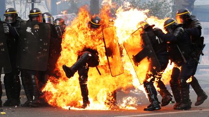 Des CRS recoivent un cocktail Molotov, le 1er mai 2017 à Paris. Six policiers ont été blessés lors de violences qui ont émaillés la manifestation organisée à l'occasion de la fête du Travail. (ZAKARIA ABDELKAFI / AFP)