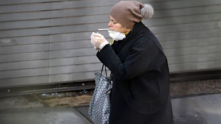 Une femme allume&nbsp;une cigarette, à New-York (Etats-Unis), le 9 avril 2020. (CINDY ORD / GETTY IMAGES NORTH AMERICA / AFP)