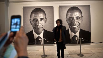 Une femme pose devant les portraits de Barack Obama, l'un inspir&eacute; de la photo officielle de 2009, l'autre de celle de 2013, rassembl&eacute;e dans une &oelig;uvre de Chuck Close, le 19 janvier 2013.&nbsp; (NICHOLAS KAMM / AFP)