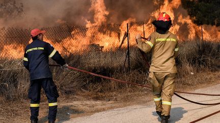 Des pompiers affrontent les flammes dans la station balnéaire de Loutraki, 80 km à l'est d'Athènes, le 17 juillet 2023. (VALERIE GACHE / AFP)