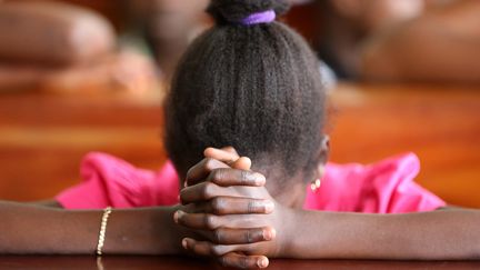 Une jeune togolaise se recueille lors de la messe dominicale dans une église de Lomé, le 16 juillet 2017.&nbsp; (PASCAL DELOCHE)