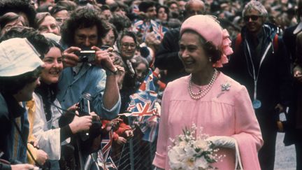 Elizabeth II lors de son jubilée dargent, le 7 juin 1977. A ce moment, le royaume uni est dans une grave crise économique. La saison 3 nde The Corwn commence aec ce chapeau. Elle avait déjà porté ce chapeau l'année d'avant pour ouvrir les JO au Canada. Elle n'aurait pas du porter ce chapeau, elle devait porter un ensemble vert beaucoup plus leger. Mais il faisait très froid le jour là.&nbsp; (FOX PHOTOS / HULTON ROYALS COLLECTION)