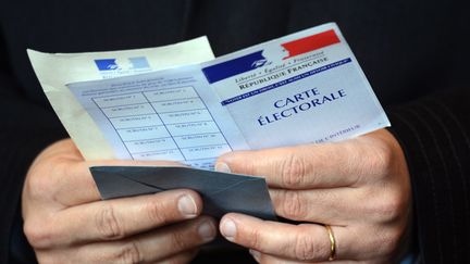 Un homme tenant sa carte électorale, à Paris (photo d'illustration) (ERIC FEFERBERG / AFP)