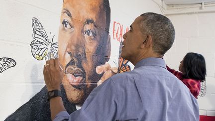 Le président sortant, accompagné de sa femme Michelle, ne s'est pas fait prier par les enfants du lieu pour se saisir d'un pinceau et décorer le portrait géant de Martin Luther King qui orne l'un des murs intérieurs du foyer, géré par de jeunes Afro-Américaines. (Michael Reynolds/SIPA)