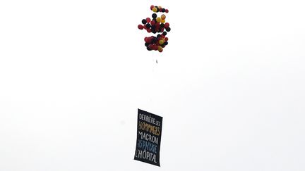 Une banderole hostile à Emmanuel Macron dans le ciel de Paris, le&nbsp;14 juillet 2020, lors de la cérémonie organisée place de la Concorde. (THOMAS SAMSON / AFP)