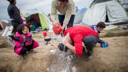 Sans doute lassé de faire la queue pour atteindre les douches, un&nbsp;migrant se lave dans le camp d'Idomeni, le 7 mars 2016.&nbsp; (KAY NIETFELD / DPA)