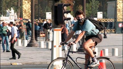 Un cycliste muni d'un masque anti-pollution, place de la Concorde, à Paris. (JOEL SAGET / AFP)