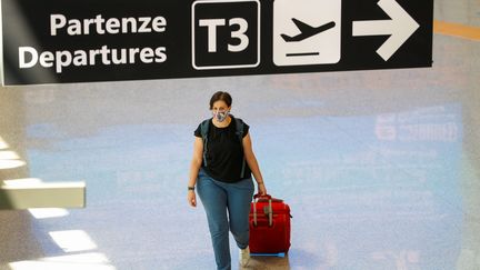 Une passagère&nbsp;marche dans l'aéroport&nbsp;Fiumicino, à Rome (Italie), le 30 juin 2020. (GUGLIELMO MANGIAPANE / REUTERS)