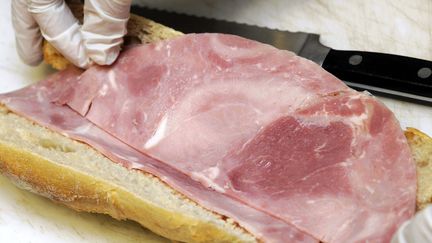 Un boulanger place une tranche de jambon à l'intérieur d'une baguette beurrée, à Nancy, le 31 janvier 2012. (ALEXANDRE MARCHI. / MAXPPP)