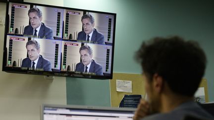 Un journaliste regarde &agrave; la t&eacute;l&eacute;vision l'interview de Nicolas&nbsp;Sarkozy sur TF1, mercredi 2 juillet 2014. (STEPHANE DE SAKUTIN / AFP)