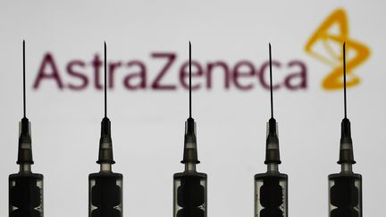 Des seringues devant le logo du groupe pharmaceutique AstraZeneca, qui teste un vaccin expérimental contre le Covid-19, ici le 12 octobre 2020 à Varsovie (Pologne). (JAKUB PORZYCKI / NURPHOTO / AFP)