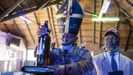 Tsietsi Makiti, fondateur de l'Eglise Gabola, en plein rituel dominical (avec sa mitre décorée de 2 mignonettes d'alcool), à la Bunny's Tavern d'Evaton en Afrique du Sud. (WIKUS DE WET / AFP)