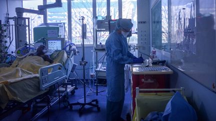 Une infirmière tsoigne une personne malade du Covid-19, dans le service de soins intensifs de l'hôpital Bichat (Paris), le 13 mars 2020. (ANNE CHAON / AFP)