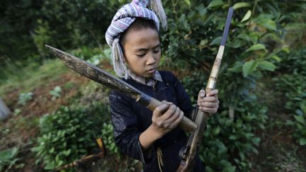 Un jeune gar&ccedil;on de l'ethnie des Miao&nbsp;remplit de poudre son fusil avant un entra&icirc;nement au tir &agrave; Basha (Chine), le 21 mai 2013. Les Miao sont la seule communaut&eacute; en Chine autoris&eacute;e &agrave; poss&eacute;der des armes &agrave; feu. (JASON LEE / REUTERS)