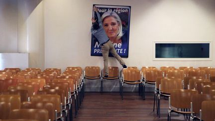 Un militant FN accroche une affiche de Marine Le Pen, dans une salle à Lille (Nord), le 7 novembre 2015. (MICHEL SPINGLER / AP / SIPA)