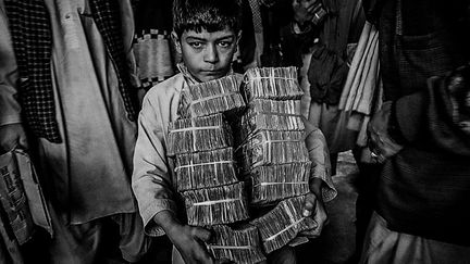 Garçon portant la monnaie afghane au marché des changes à Herat, Afghanistan 2001
 (Majid Saeedi /Getty Images)