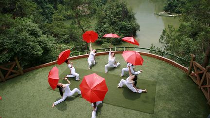 Chorégraphie de yoga pour sept parapluies rouges, au dessus du lac Baofeng, dans la province du Hunan, au centre de la Chine. (WU YONGBING / XINHUA)