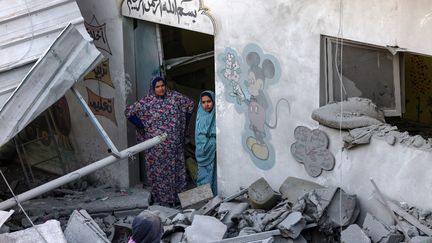 Une femme et une fille se tiennent au milieu des décombres d’un jardin d’enfants touché par les bombardements israéliens à Rafah, dans le sud de la bande de Gaza, le 9 décembre 2023. (SAID KHATIB / AFP)