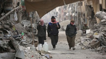 Des Syriens au milieu des décombres dans la ville de Raqqa en Syrie, le 11 janvier 2018. (DELIL SOULEIMAN / AFP)