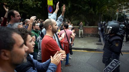 Des&nbsp;policiers font face à des Catalan, dimanche 1er octobre, à Barcelone en Espagne. (ALAIN PITTON / NURPHOTO / AFP)