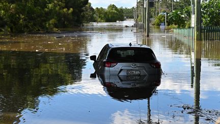 Une voiture piégée par les eaux dans le nord-est de Sydney (Australie), le 24 mars 2021. (STEVEN SAPHORE / ANADOLU AGENCY / AFP)