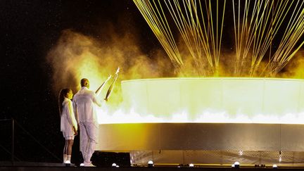 Le moment inoubliable de ce relais de la flamme olympique. Le judoka Teddy Riner et la sprinteuse Marie-José Pérec allument la vasque au jardin des Tuileries (Paris), le soir de la cérémonie d'ouverture, le 26 juillet 2024 (AGENCE KMSP / KMSP / AFP)