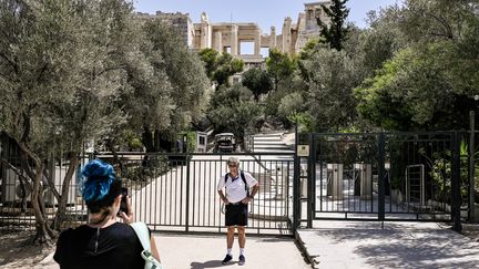 Des touristes devant le site archéologique de l'Acropole, à Athènes (Grèce), fermé à cause de la canicule, le 14 juillet 2023. (SPYROS BAKALIS / AFP)