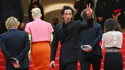 Adrian Brody fait le signe de la victoire aux photographes pendant que le reste de l'équipe monte les marches&nbsp; (CHRISTOPHE SIMON / AFP)