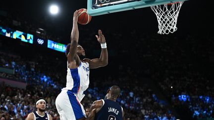 Le Français Guerschon Yabusele dunke par dessus la star américaine LeBron James, lors de la finale des Jeux olympiques, le 10 août 2024 à Bercy. (ARIS MESSINIS / AFP)