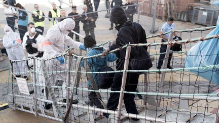 Des migrants quittent le navire humanitaire "Ocean Viking" à Toulon, le 11 novembre 2022. (VINCENZO CIRCOSTA / AFP)