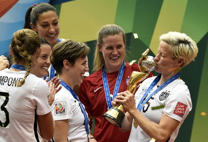 La milieu de terrain américaine Megan Rapinoe embrasse la Coupe du monde, sous les yeux de ses équipières, à l'issue de la finale Etats-Unis-Japon à Vancouver, le 5 juillet 2015. (FRANCK FIFE / AFP)