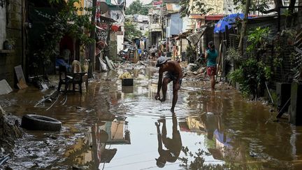 Un homme dans une rue inondée de San Mateo, dans la province de Rizal, aux Philippines, après le passage du typhon Noru, le 26 septembre 2022. (JAM STA ROSA / AFP)