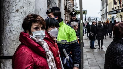 Des visiteurs de Venise (Italie) portent des masques de protection, le 23 février 2020, alors que l'épidémie prend de l'ampleur dans le pays. (MANUEL ROMANO / AFP)