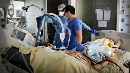 Des médecins au chevet d'un patient hospitalisé en réanimation, le 8 mars 2021 à Boulogne-Billancourt (Hauts-de-Seine). (ALAIN JOCARD / AFP)