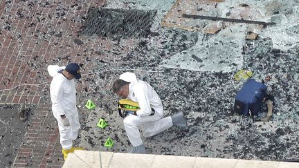 Des enqu&ecirc;teurs cherchent des indices, le 16 avril, autour du lieu de la premi&egrave;re explosion qui a frapp&eacute; Boston la veille. (ELISE AMENDOLA / AP / SIPA)