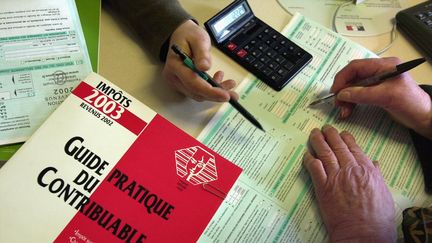 Une employée d'un centre des impôts aide une contribuable à remplir sa feuille de déclaration de revenus. (Photo d'illustration) (MYCHELE DANIAU / AFP)