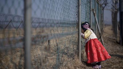 Une petite fille en habit traditionnel regarde la Cor&eacute;e du Nord &agrave; travers un grillage &agrave; Imjin Gak (Cor&eacute;e du Sud), le 19 f&eacute;vrier 2015. (ED JONES / AFP)