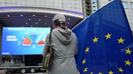 Une femme qui tient un drapeau européen en attendant les résultats des élections européennes devant le Parlement européen à Bruxelles.&nbsp; (JOHN THYS / AFP)