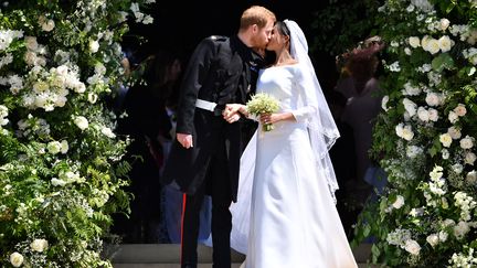 Le prince Harry et la duchesse Meghan s'embrassent à la sortie de la chapelle Saint George, à Windsor (Royaume-Uni), le 19 mai 2018. (BEN STANSALL / AFP)