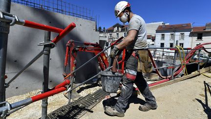 Un ouvrier porte un sceau sur un chantier. (Photo d'illustration) (ALEXANDRE MARCHI / MAXPPP)