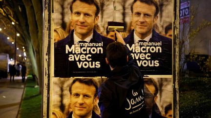 Un membre des Jeunes avec Macron collent des affiches du parti présidentiel, à Vanves (Hauts-de-Seine), le 16 mars 2022. (LUDOVIC MARIN / AFP)