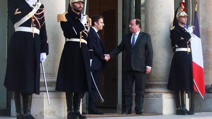 Emmanuel Macron serre la main de l'ancien président François Hollande après une réunion au palais de l'Élysée à Paris, le 25 février 2022. (MOHAMMED BADRA / MAXPPP)