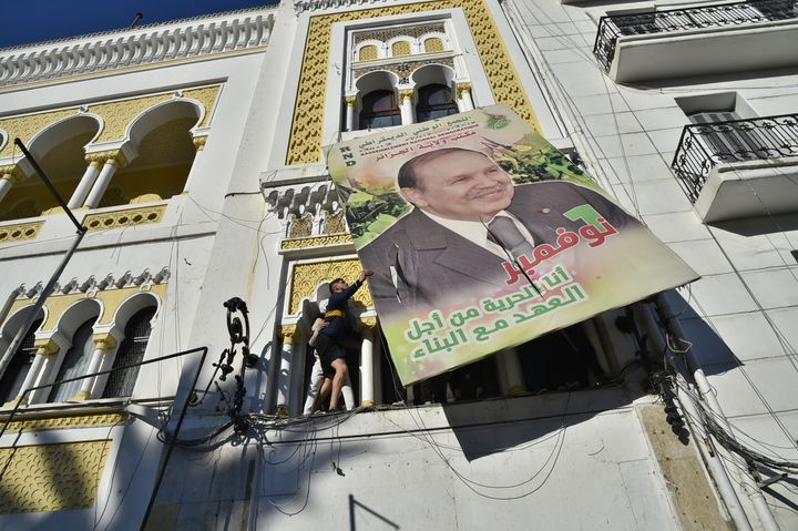 Un manifestant fait tomber un portrait géant du président algérien Abdelaziz Bouteflika à Alger, le 22 février 2019, lors d'une manifestation contre sa candidature à l'élection présidentielle. (RYAD KRAMDI / AFP)