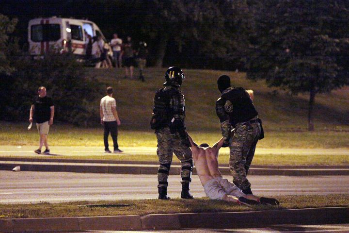 Deux militaires anti-émeutes tirent par les bras un manifestant, le 9 août 2020, à Minsk.&nbsp; (SIARHEI LESKIEC / AFP)