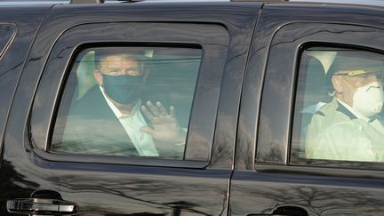 Donald Trump&nbsp;salue&nbsp;un groupe de supporters depuis une voiture, le 4 octobre 2020, devant l'hôpital Walter Reed, à Bethesda, dans le Maryland. (ALEX EDELMAN / AFP)