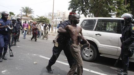 Un manifestant de l'opposition arr&ecirc;t&eacute; mercredi 15 f&eacute;vrier &agrave; Dakar, au S&eacute;n&eacute;gal. (MAMADOU TOURE BEHAN / AFP)