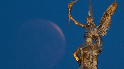 A Dresde (Allemagne), la Lune a joué à cache-cache avec une statue de l’Ecole des beaux-arts. (SEBASTIAN KAHNERT / DPA-ZENTRALBILD / AFP)