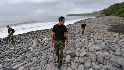 Des officiers de la gendarmerie &agrave; la recherche de d&eacute;bris &eacute;ventuels du vol MH370 de la Malaysia Airlines, sur une plage de Sainte-Marie de la R&eacute;union (La R&eacute;union), le 8 ao&ucirc;t 2015. (RICHARD BOUHET / AFP)