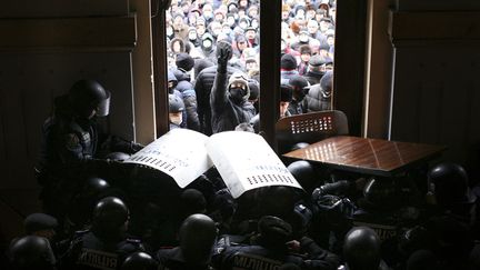 Des manifestants anti-gouvernementaux tentent de p&eacute;n&eacute;trer dans un b&acirc;timent administratif gard&eacute; par des policiers &agrave; Tchernivtsi (Ukraine), le 24 janvier 2014. (REUTERS)