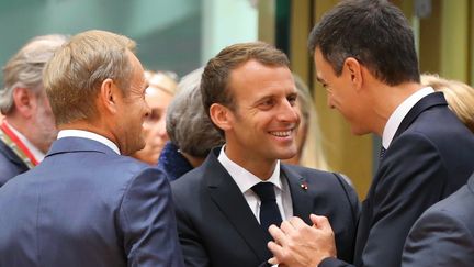 Emmanuel Macron au milieu du&nbsp;président du Conseil européen&nbsp;Donald Tusk (à gauche) et du Premier ministre espagnol Pedro Sanchez, lors d'un sommet européen à Bruxelles le 28 juin 2018. (DURSUN AYDEMIR / ANADOLU AGENCY / AFP)